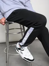 Pantalón de jogging negro con puños ajustados, cortes laterales y cambio de color en la parte inferior de la pierna.