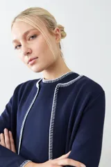 Saco tejido azul marino con pespuntes blancos en cuello, solapa, borde y puños.