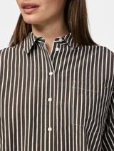 Camisa de popelina con mangas cortas, cuello clásico y cierre frontal de botones. Presenta un estampado de rayas verticales finas en tonos marrón oscuro y blanco.