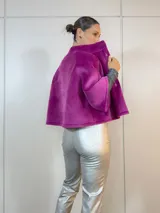 Chaqueta corta fucsia de terciopelo con cuello alto, mangas 3/4 amplias y cierre frontal con botones.