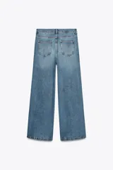 Pantalón de jean de tiro medio, pierna ancha y largo hasta el tobillo. Cintura con trabillas ajustable con cordones a contraste. Cinco bolsillos. Efecto lavado. Cierre frontal con cremallera y botón.