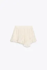 Minifalda color crema con cintura elástica y volados en el ruedo. Tiene short interno.