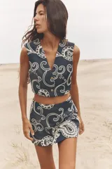Falda pantalón corta de tiro alto color azul denim con bordados florales blancos.