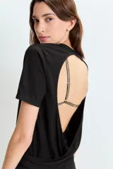 Remera negra con espalda descubierta y tiras doradas de corpiño a la vista.