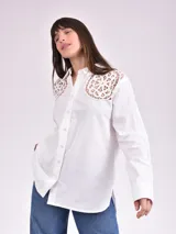 Camisa blanca de manga larga con detalles de encaje en los hombros.