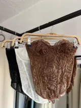 Corset blanco con encaje floral, corte strapless y ballenas verticales.