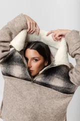 Buzo de lana color beige con cuello alto con cierre y aplique de corderito en el cuello. De mangas rectas y corte amplio.