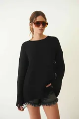 Sweater negro de tejido de punto grueso, con cuello redondo, mangas largas y corte holgado. Presenta terminaciones deshilachadas en ruedo y puños.