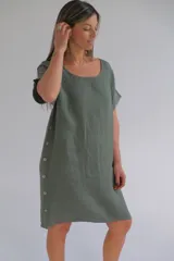 Vestido verde seco de lino italiano, corte suelto, escote redondo, manga corta y botones decorativos en los costados.