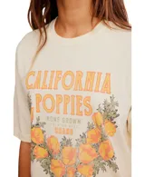 Remera color crema con estampado de flores de amapola color naranja y texto en la parte delantera.
