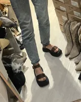 Sandalias de cuero marrón con plataforma y tira ancha sobre los dedos.