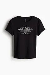 Remera negra entallada corta en punto acanalado de algodón con estampa frontal de pastelería francesa. Costuras planas para una comodidad óptima.