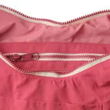 Bolso tipo hobo color rosado, con correa de hombro ajustable y bolsillo externo.