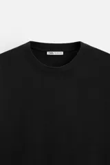 Camiseta blanca de algodón compacto, corte relaxed fit, cuello redondo y mangas cortas.