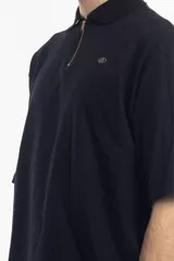 Remera polo negra de manga corta con cierre dorado en el cuello y logo bordado en el pecho.