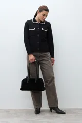 Chaqueta de tejido negro, de manga larga y corte recto, con cuello y bordes de bolsillo con ribete de punto en color crudo/beige.