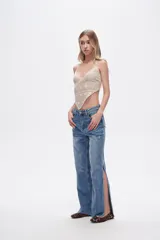 Pantalón de jean azul de tiro alto, corte recto y aberturas laterales en el ruedo.