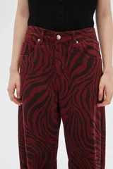 Pantalón de jean de tiro alto con estampado animal print de cebra en tonos borgoña y negro.