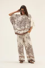 Pantalón palazzo de seda color crema con estampado floral en tonos marrones y cintura elastizada con cordón ajustable.