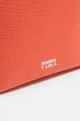 Bolso de mano mediano marca Bimba y Lola, color naranja, confeccionado en cuero con textura granulada. Tiene doble asa corta, correa bandolera ajustable y extraíble, logo estampado en el frente y herrajes plateados. El interior cuenta con etiqueta de tejido con el logo de la marca.