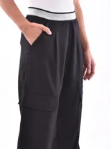 Pantalón negro de corte ancho con cintura elástica y bolsillos cargo.