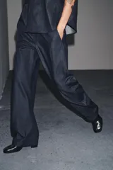 Pantalón de denim azul oscuro, de tiro medio y corte ancho, con cintura elástica en la parte trasera y cierre frontal con cremallera y botón.