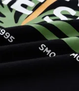 Remera de algodón negra, corte oversized, con estampa frontal de una flor estilizada en tonos rojo, amarillo y verde, y el texto "Balance ESTD. 1995" en blanco.