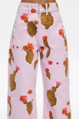 Pantalón de jean color lila con estampado de cactus marrones con flores naranjas. Corte recto, tiro medio y largo tobillero.
