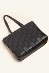 Cartera tipo tote bag de cuero vacuno trenzado a mano, con diseño de tejido ajedrez. Cuenta con doble asa de hombro y cierre superior.