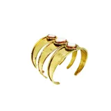 Brazalete ancho de bronce dorado, con textura martillada, compuesto por tres bandas unidas y adornado con tres piedras engarzadas: una central ovalada de nácar blanco y dos laterales cuadradas de nácar blanco.