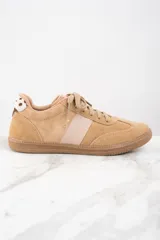 Zapatillas bajas de gamuza color beige con cordones y suela de goma marrón. Detalle de cuero liso color crema en el lateral y parche con estampado de vaca en el talón.