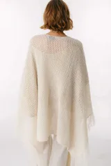 Ruana de punto color beige con cuello alto y flecos.