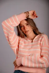 Sweater de punto color beige con rayas horizontales blancas, cuello polo con cierre de cremallera y mangas largas.