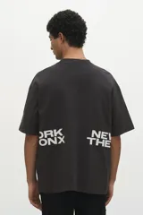 Remera negra de corte holgado con cuello redondo y mangas cortas. Estampado frontal con la inscripción "ORK XON NEW THE".