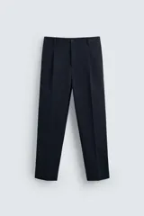 Pantalón de vestir azul marino, de corte recto, con bolsillos laterales y traseros. Se ajusta a la cintura con cinturón de cuero marrón.