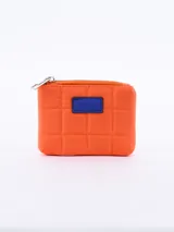 Monedero cuadrado acolchado color naranja con cierre superior y parche azul.