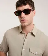 Camisa de hombre de manga corta en lino color blanco, con cuello clásico, botonadura frontal y bolsillo de parche en el pecho. Corte recto.