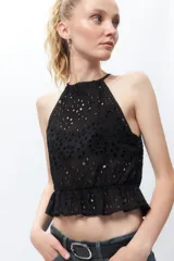 Top bordado negro sin mangas con tira reguladora en el cuello y elástico con volado en la cintura.