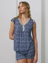 Conjunto de pijama marca René Rofé, compuesto por short y remera de tejido soft estampado con flores rosas sobre fondo blanco. Remera de escote en V con aplique de puntilla, botones y detalle plisado. Short con cintura elastizada.