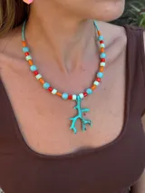 Collar corto con cuentas de colores y dije de coral de resina. Se cierra con cadena de acero quirúrgico y ganchito para regular el largo.