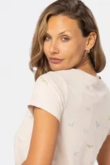 Remera color beige con estampado de aves en tonos celeste, lila y dorado.