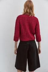 Chaqueta roja de tweed con cuello redondo, manga francesa, bolsillos delanteros y cierre frontal con botones dorados.