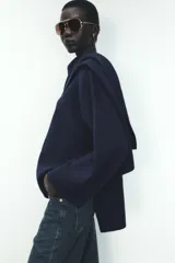 Abrigo azul marino de punto con cuello redondo y manga larga. Incluye bufanda integrada y cierre frontal con botón.