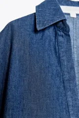 Camisa corta de denim azul, con cuello solapa, escote en pico y mangas cortas.