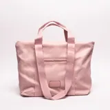 Bolso tote rosa claro de material sintético, con asas de cinta tejida y bolsillo exterior frontal.