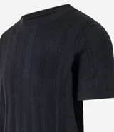 Remera negra de algodón con textura trenzada, cuello redondo y mangas cortas.