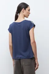 Blusa de manga corta con cuello redondo, confeccionada en tela satinada con estampado abstracto en azul marino y blanco.