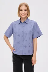 Camisa blanca de algodón con bordado calado de flores, cuello camisero, corte recto y mangas cortas.