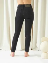 Pantalón de jean negro, corte skinny, tiro alto y largo al tobillo.