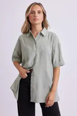 Camisa verde de corte holgado, con cuello clásico, cierre frontal con botones y mangas cortas con dobladillo.